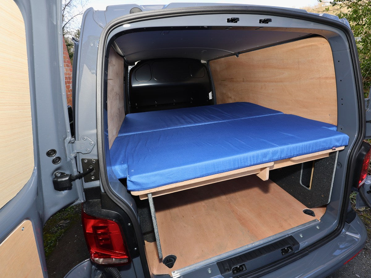 Blue mattress on top of the FMR camper converter kit in a tradespersons van.