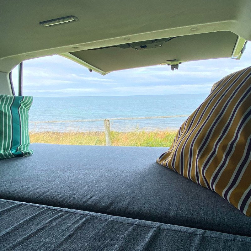 View of a Welsh beach from the back of a transit van converted to a camper by Orbvans.