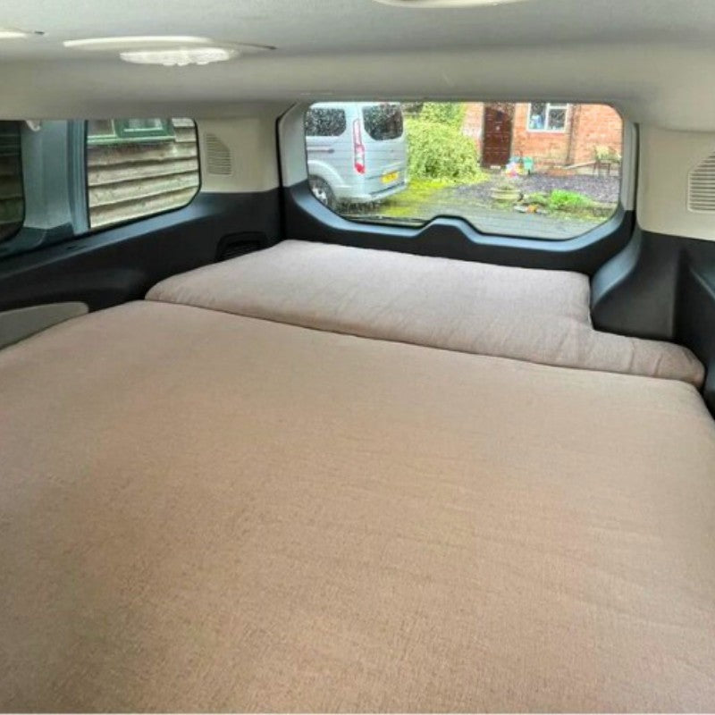Bed installation that matches the interior van design on top of a FMR camper converter kit.