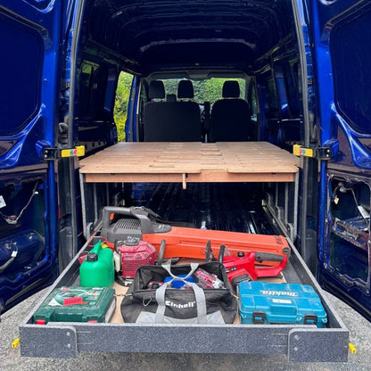 FMR camper van converter kit with fullwidth drawer module attached storing work tools like drills and leaf blowers.