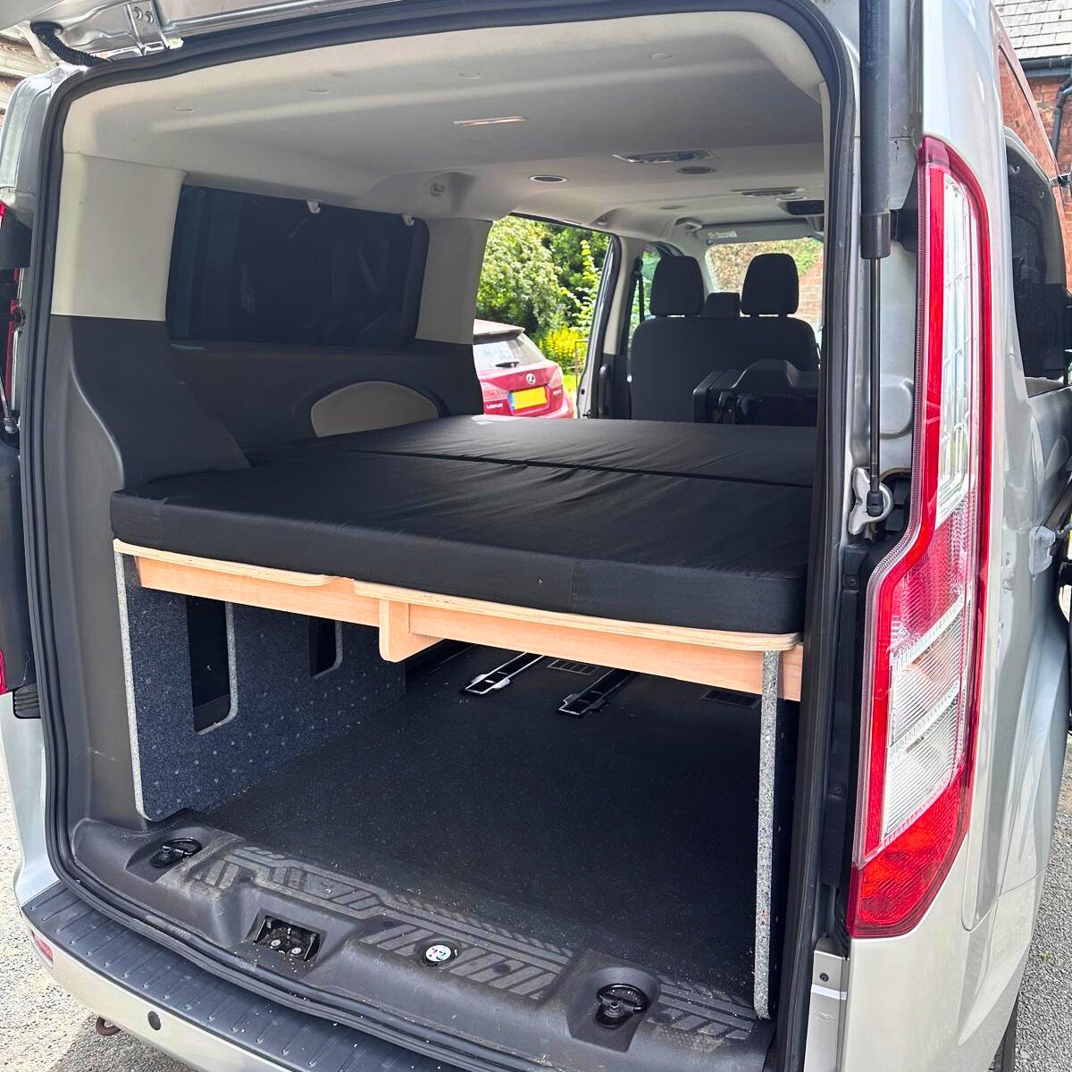Black mattress on top of the Orbvans camperbed converter kit in a Ford Torneo.